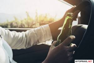 Человек держащий бутылку пива за рулем авто